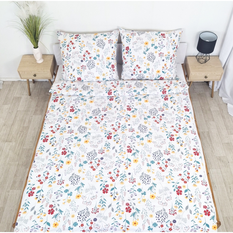 Pościel z Kory PREMIUM Lilia Wytrzymała- Kolorowa łąka na bieli 1345B, rozłożona na łóżku